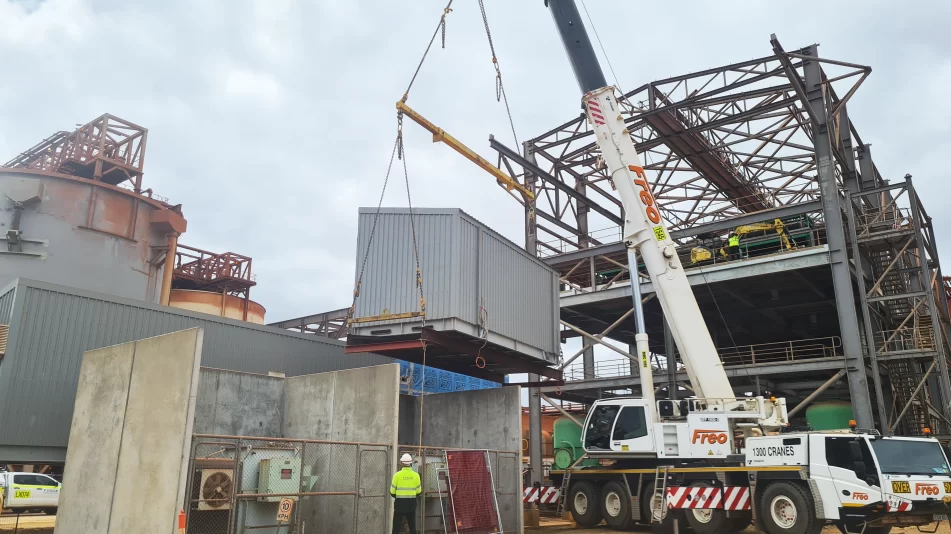 A crane lifting a crate at the Worsley Mine demolition site overseen by a Focus Demolition employee in PPE.