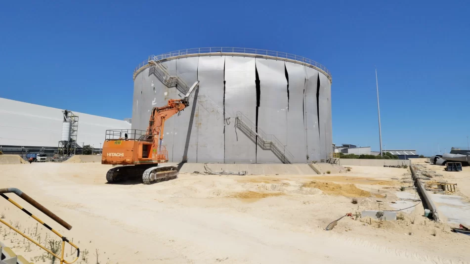 Works beginning at the Kwinana Tanks Industrial Demolition site where steel oil tanks are being taken apart by an excavator.