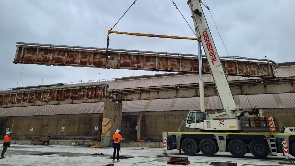 Demolition at the the Fremantle Port RC07 showing a crane lifting a long, rusty metal structure which is weathered and corroded.